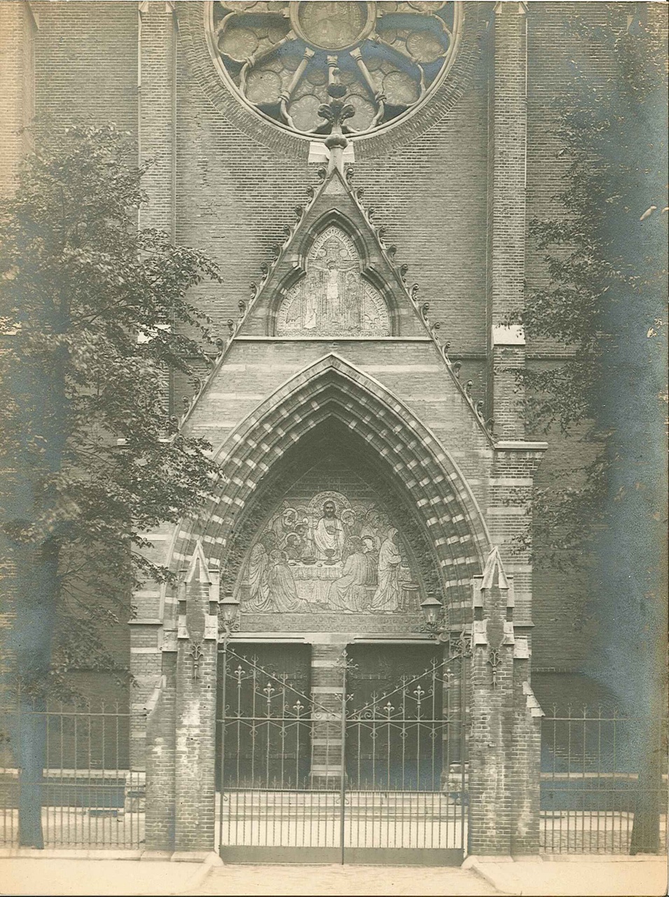 Foto van twee mozaïekpanelen boven een kerkpoort te Amsterdam.