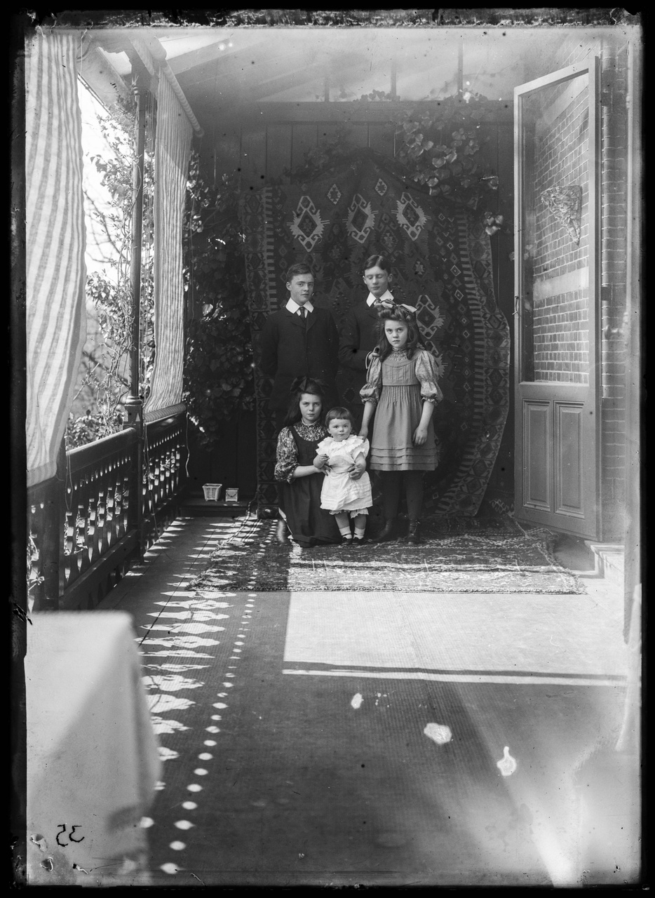 Glasnegatief van een foto van de vijf kinderen van Jos Cuypers in een serre-achtige ruimte.
