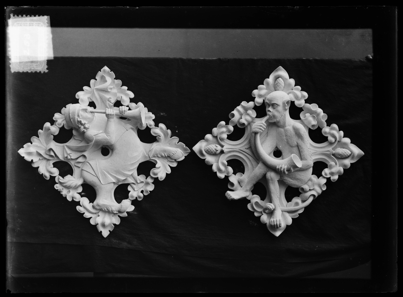 Glasnegatief van foto van producten uit de Cuypers' Kunstwerkplaatsen uit kist met nummer 24: "Twee gipsen muurornamenten met afbeeldingen van hoorn- of schalmeiblazers".