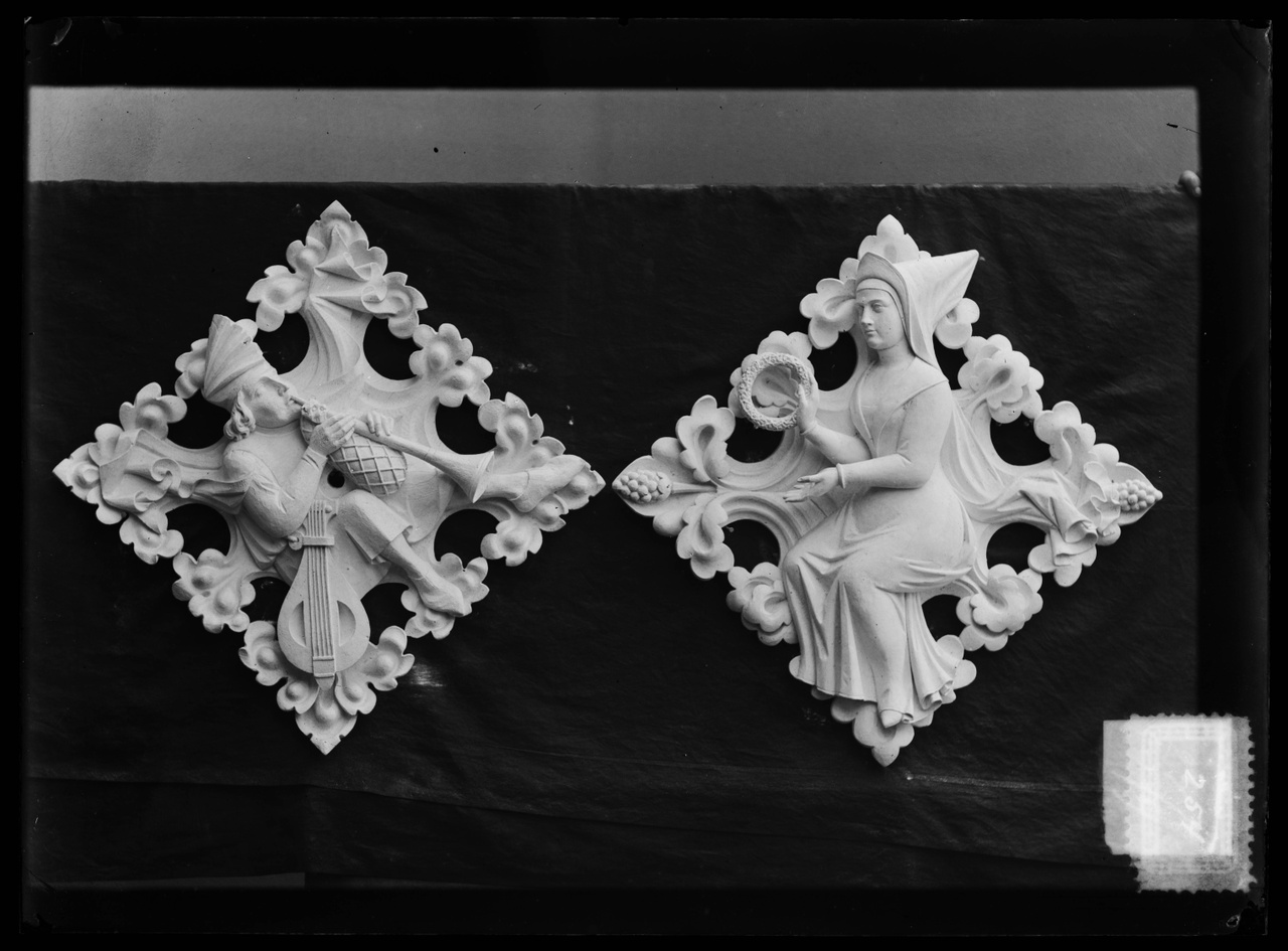 Glasnegatief van foto van producten uit de Cuypers' Kunstwerkplaatsen uit kist met nummer 24: "Twee gipsen muurornamenten met afbeeldingen van een trompetblazer en van een middeleeuwse dame".
