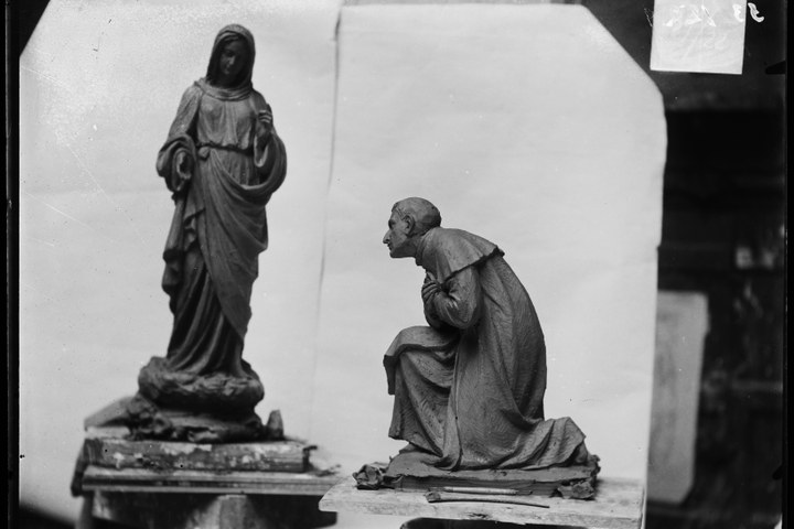Glasnegatief van foto van producten uit de Cuypers' Kunstwerkplaatsen: "Foto van een beeldje van een vrouw met hoofddoekk en van een beeldje van een knielende priester".