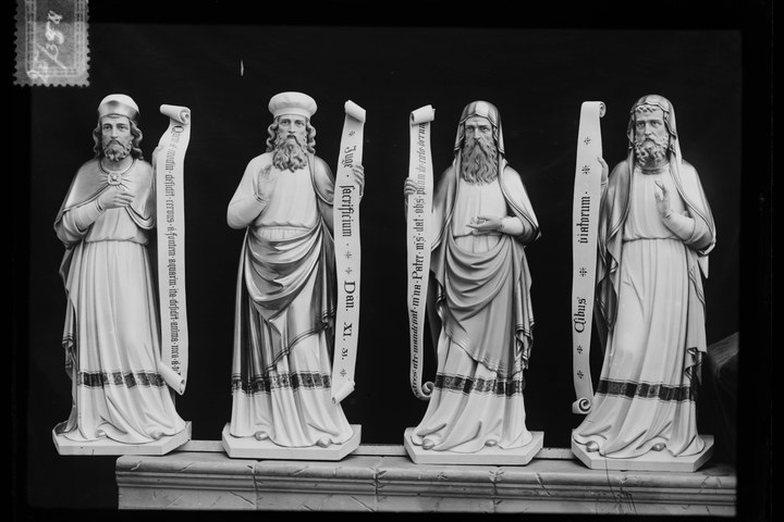 Glasnegatief van foto van producten uit de Cuypers' Kunstwerkplaatsen: "Foto van vier beelden van mannelijke heiligen met banderoles.".