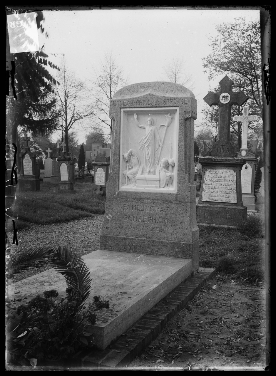 Glasnegatief van foto van producten uit de Cuypers' Kunstwerkplaatsen: "Foto van een grafmonument met meerdere graven op de achtergrond".