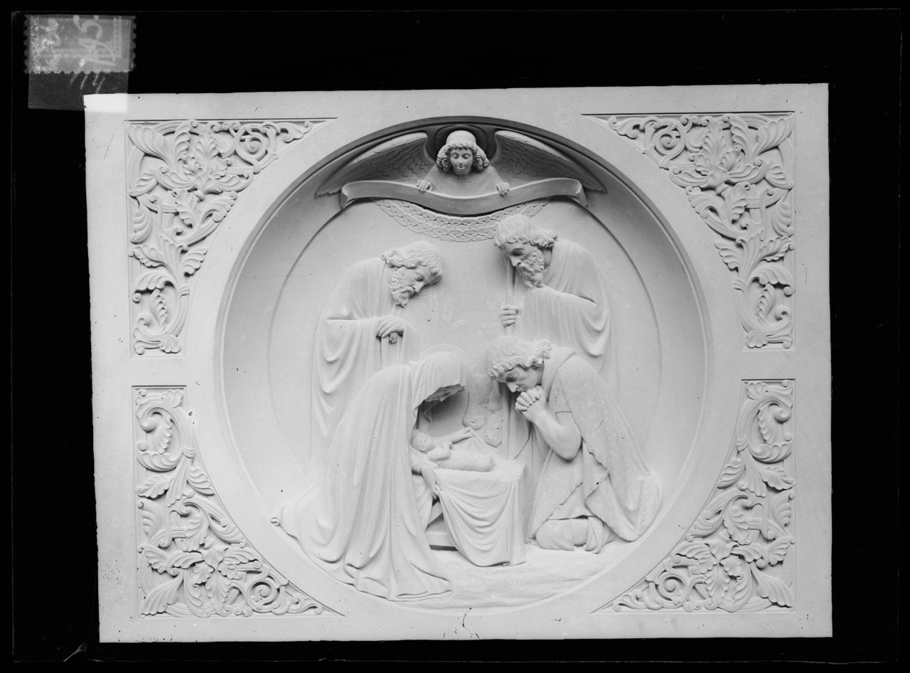 Glasnegatief van foto van producten uit de Cuypers' Kunstwerkplaatsen: "Foto van een paneel met daarop het Christuskind in een kribbe met daar omheen vier personen".